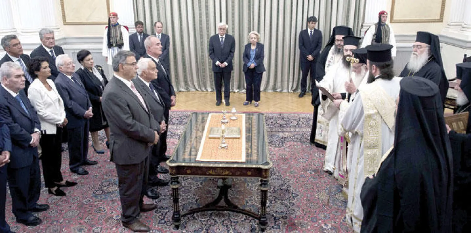 أعضاء الحكومة الانتقالية الجديدة يؤدون اليمين الدستورية أمام الرئيس اليوناني بروكوبيس بافلوبولوس ورئيسة الوزراء الجديدة  فاسيليكي ثانوس بالقصر الرئاسي في أثينا أمس (أ.ف.ب)