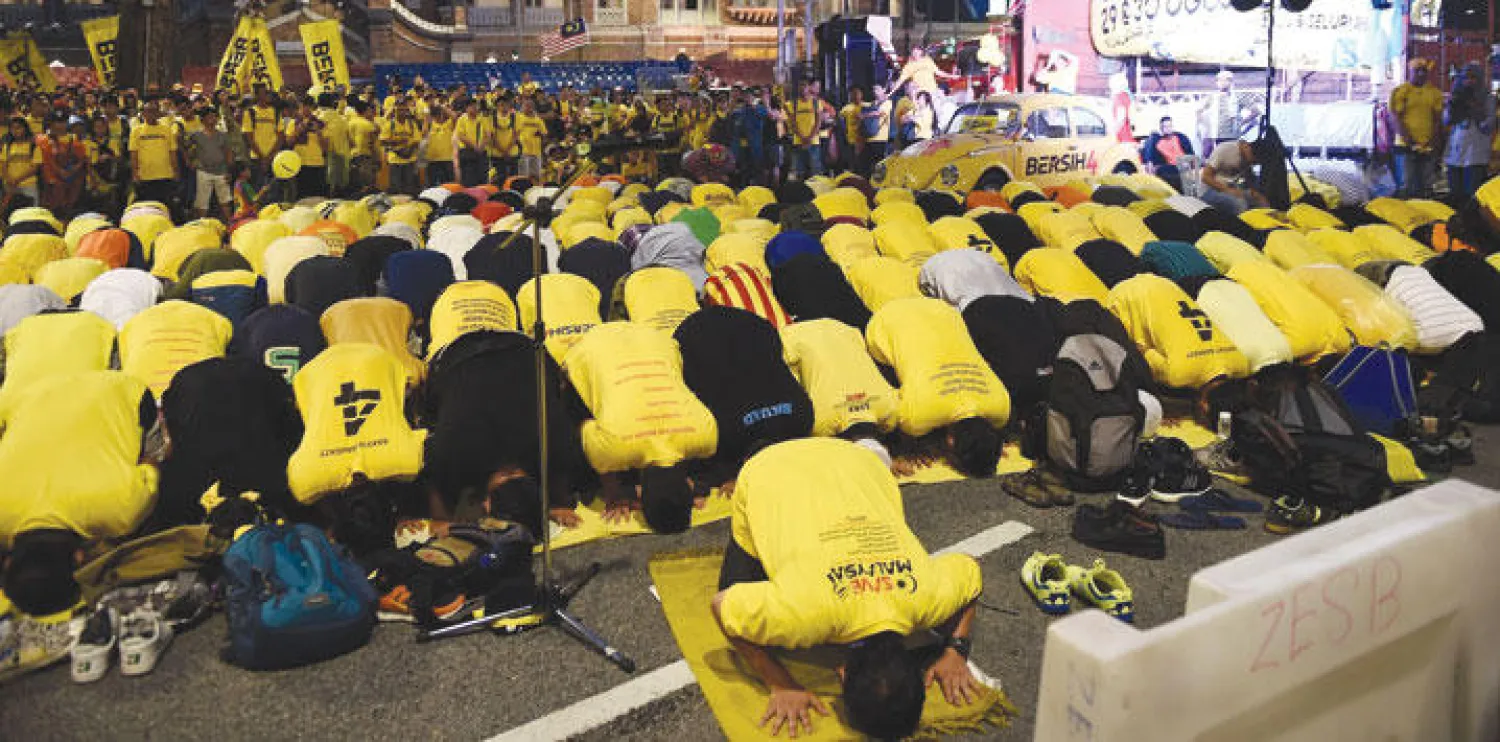 المتظاهرون في وسط كوالالمبور يؤدون صلاة الفجر أمس (أ.ف.ب)