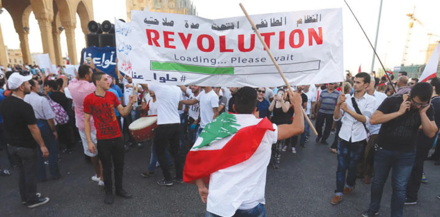 نشطاء لبنانيون يرفعون أعلام بلادهم في مظاهرة ضد الفساد والطائفية في العاصمة بيروت الأسبوع الماضي (أ.ف.ب)