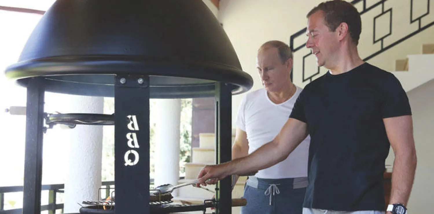 الرئيس الروسي فلاديمير بوتين ورئيس الوزراء ديمتري ميدفيديف يشويان اللحم في سوتشي جنوب البلاد أمس (إ.ب.أ)