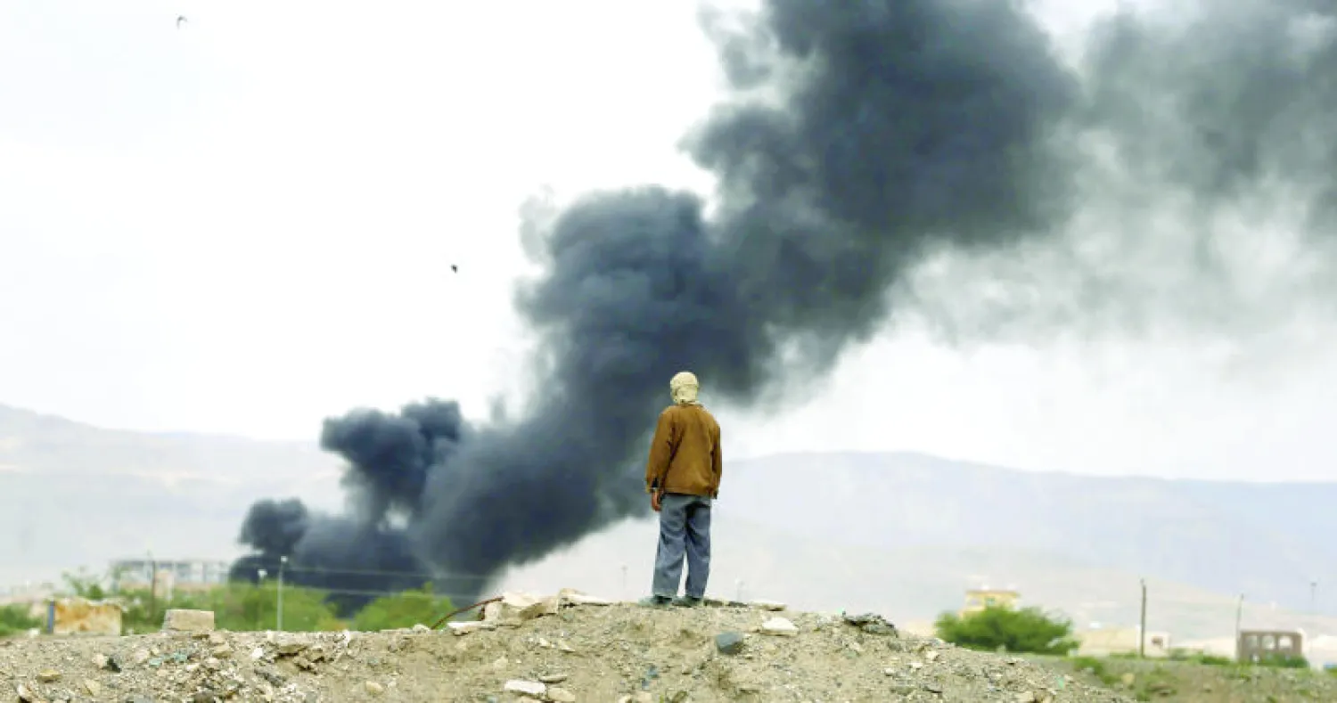 يمني يراقب الدخان المتصاعد من موقع الأكاديمية العسكرية الذي استهدفته قوات التحالف في صنعاء أمس (رويترز)