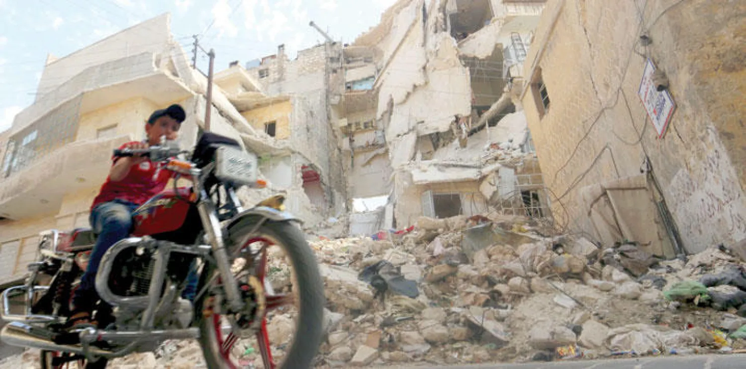 شاب يقود دراجته النارية في شوارع حلب القديمة المدمرة أمس (رويترز)
