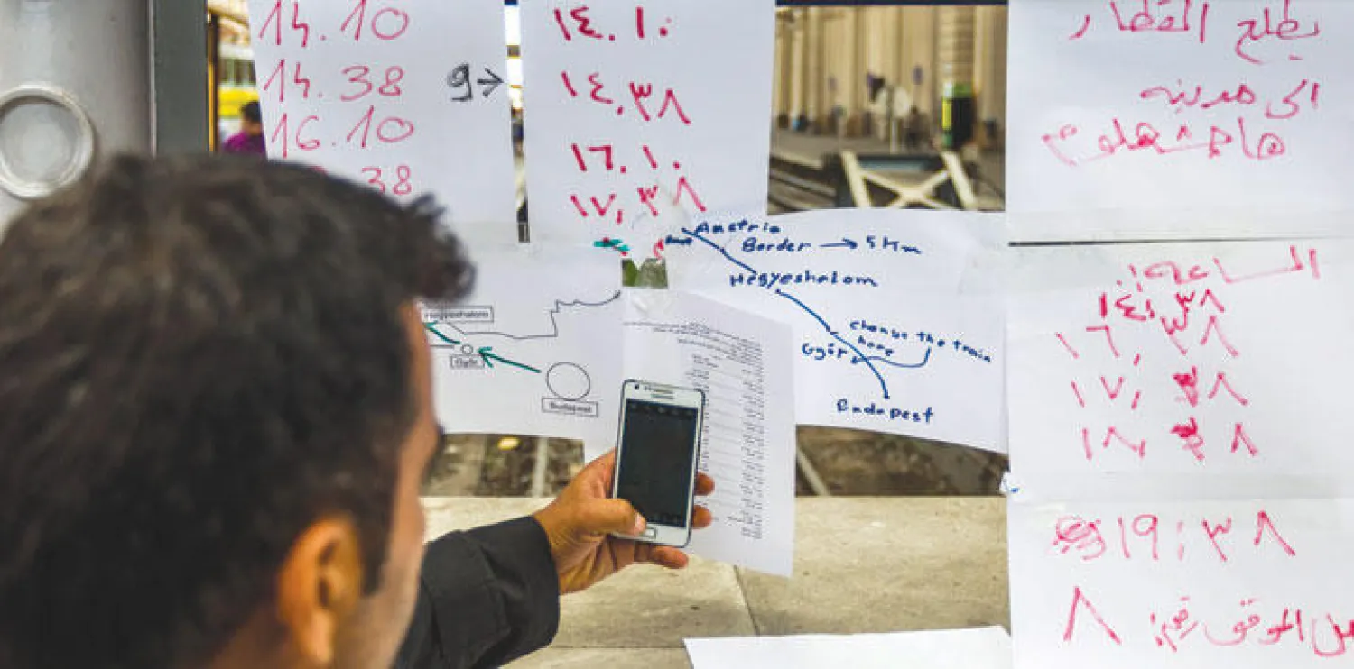 لاجىء عربي يطالع جدولا بالعربية بمواعيد الرحلات في محطة القطار الرئيسية في بودابست أمس (أ.ب)