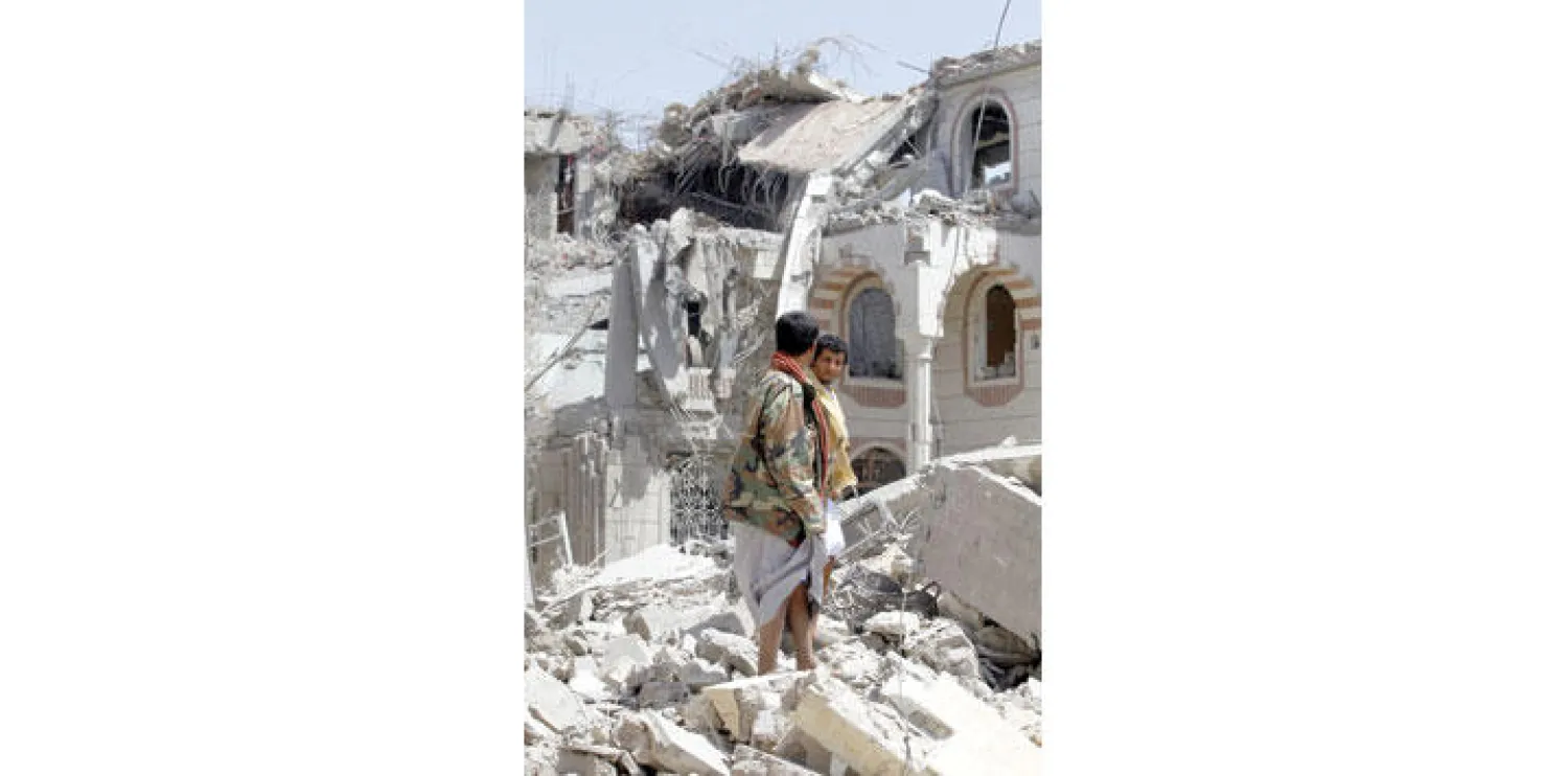 مسلحان أمام مبنى تابع للحوثيين استهدفه طيران التحالف العربي من أجل الشرعية في صنعاء أمس (إ.ب.أ)