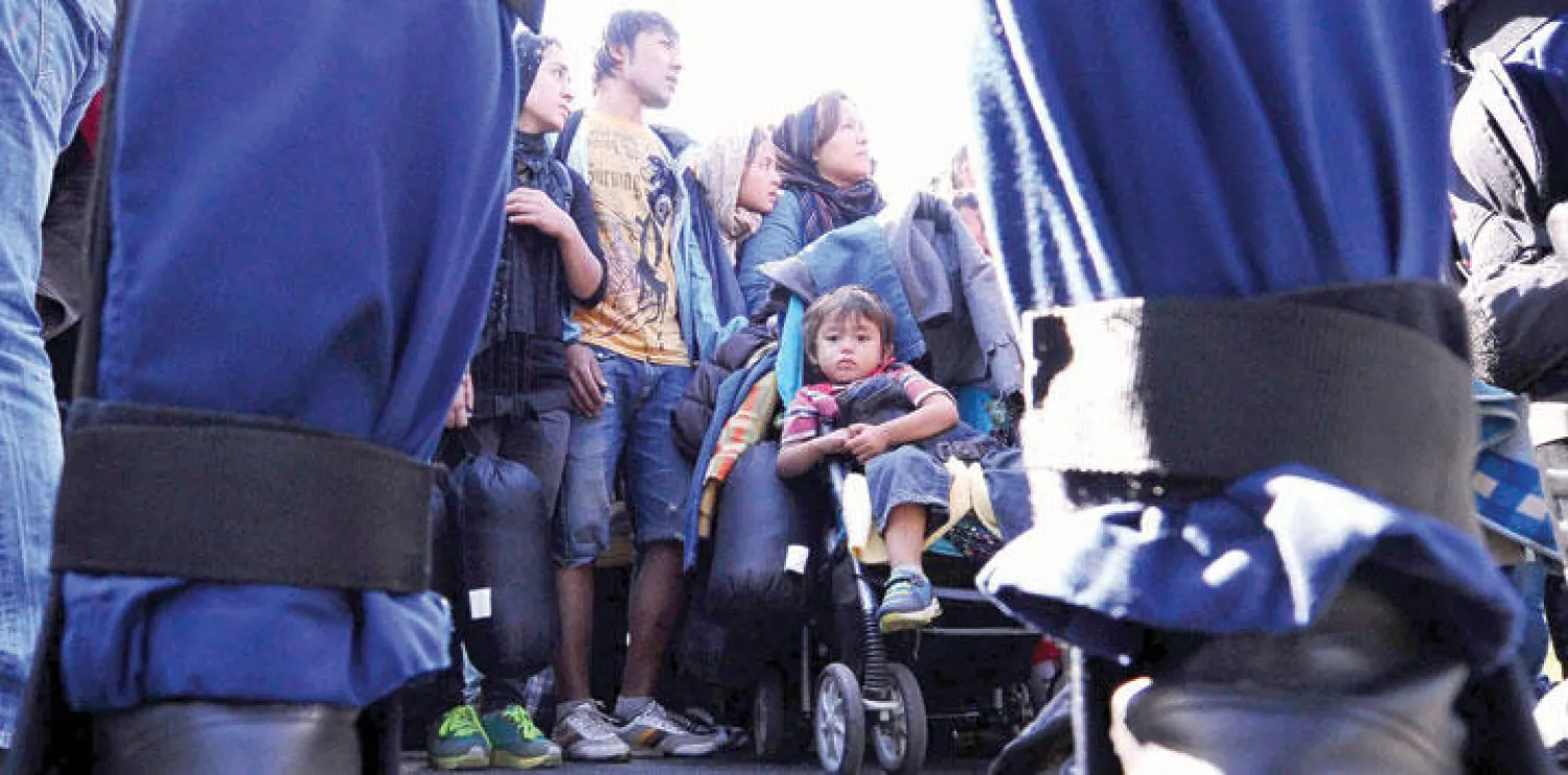 شرطي ضمن صف من عناصر الأمن المجريين مكلفين بضبط مجموعة من اللاجئين في قرية روزسكي على الحدود المجرية - الصربية أمس (أ.ف.ب)