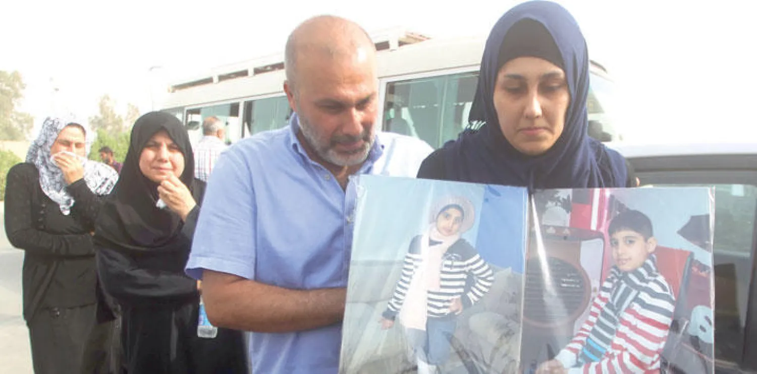 زينب عباس تحمل صورتي ابنتها زينب وابنها حيدر خلال تشييعهما في كربلاء أمس (أ.ف.ب)