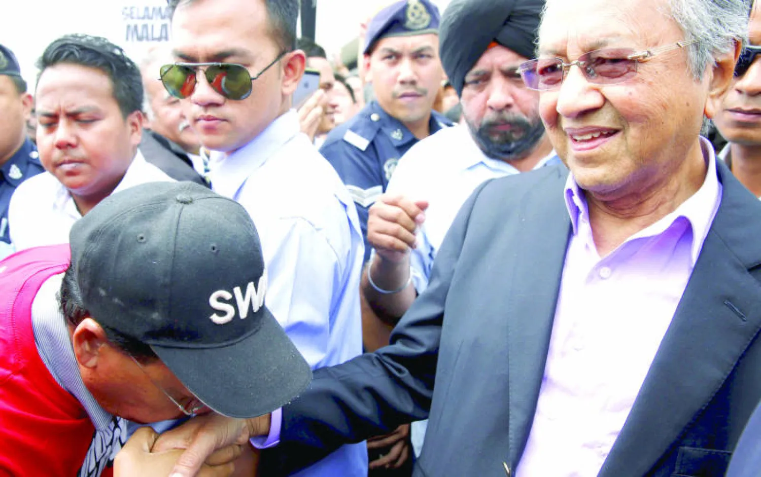 شاب يقبّل يد رئيس الوزراء الماليزي السابق مهاتير محمد الذي سيخضع لاستجواب الشرطة بسبب تعليقات ضد رئيس الحكومة (رويترز)