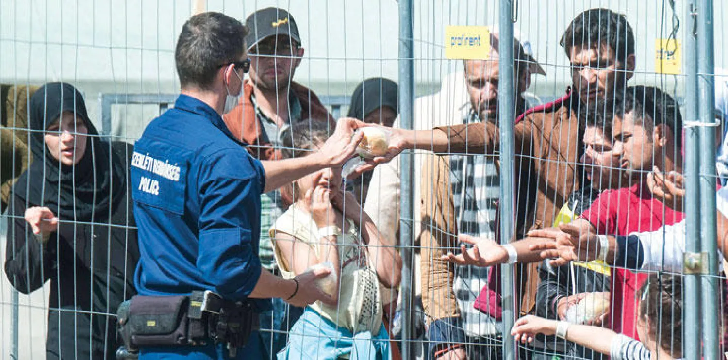 رجال شرطة مجريون يوزعون طعاما وشرابا على المهاجرين في مخيم يبعد 180 كيلومترا عن جنوب شرقي العاصمة المجرية بودابست (أ.ب )