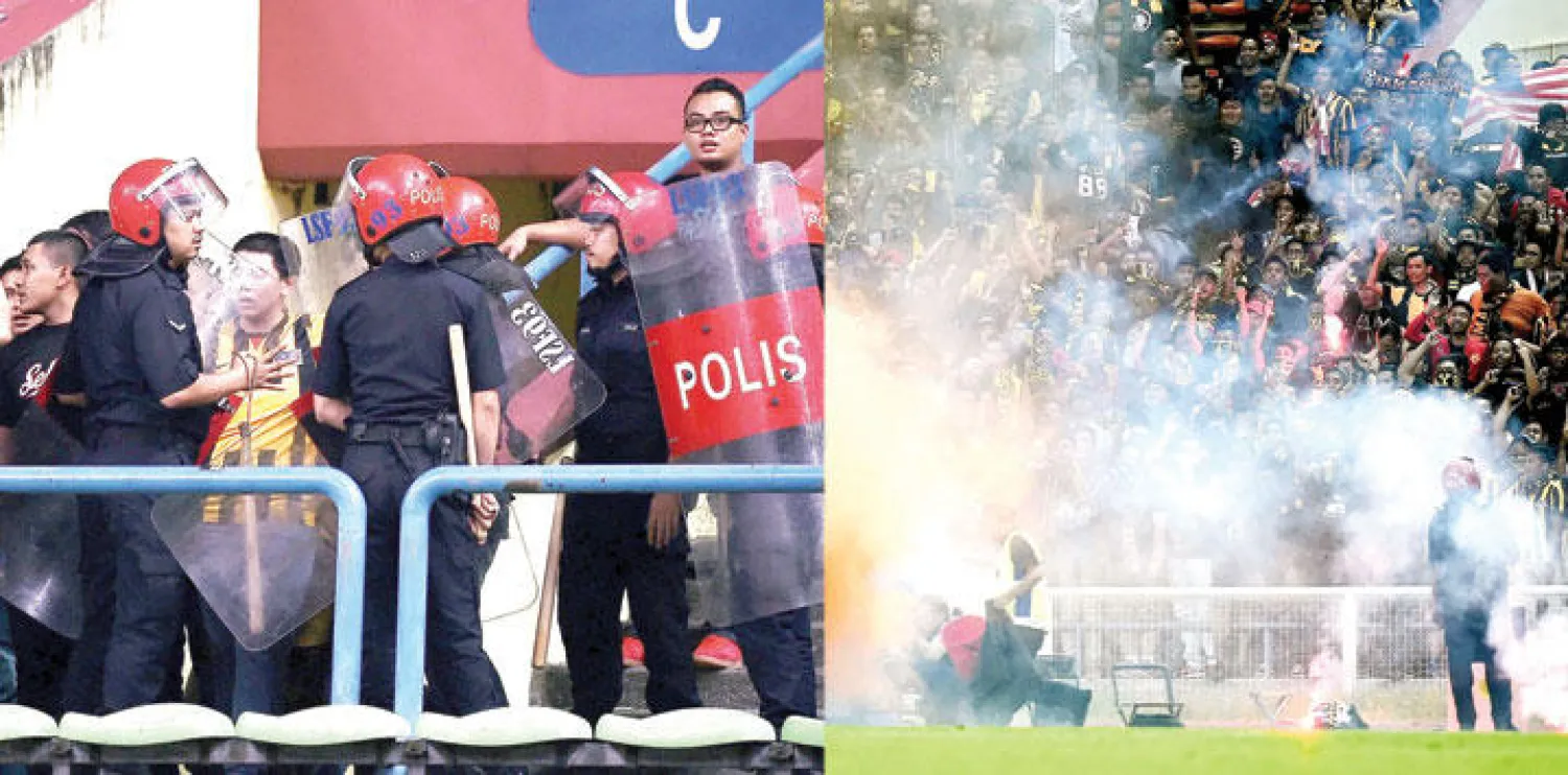 أحداث الشغب في مباراة السعودية وماليزيا اضطرت الحكم إلى إيقافها قبل استنفاد الوقت الأصلي (أ.ف.ب)  -  الشرطة الماليزية خلال إلقائها القبض على بعض المشاغبين (أ.ف.ب)