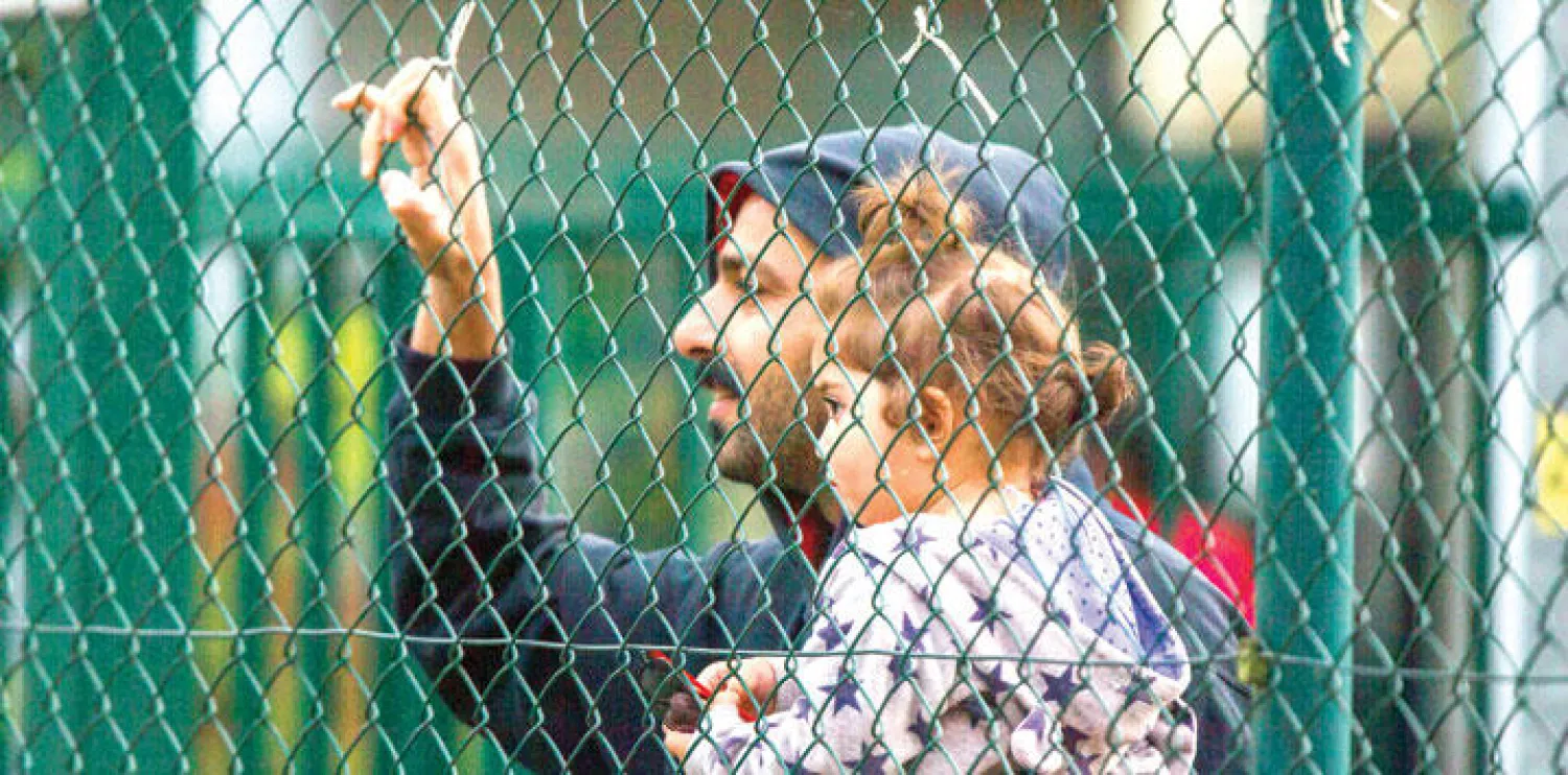 لاجئ يحمل طفلته أمام مركز استقبال لاجئين في مكلنبورغ في هورست غرب ألمانيا أمس (أ.ب)