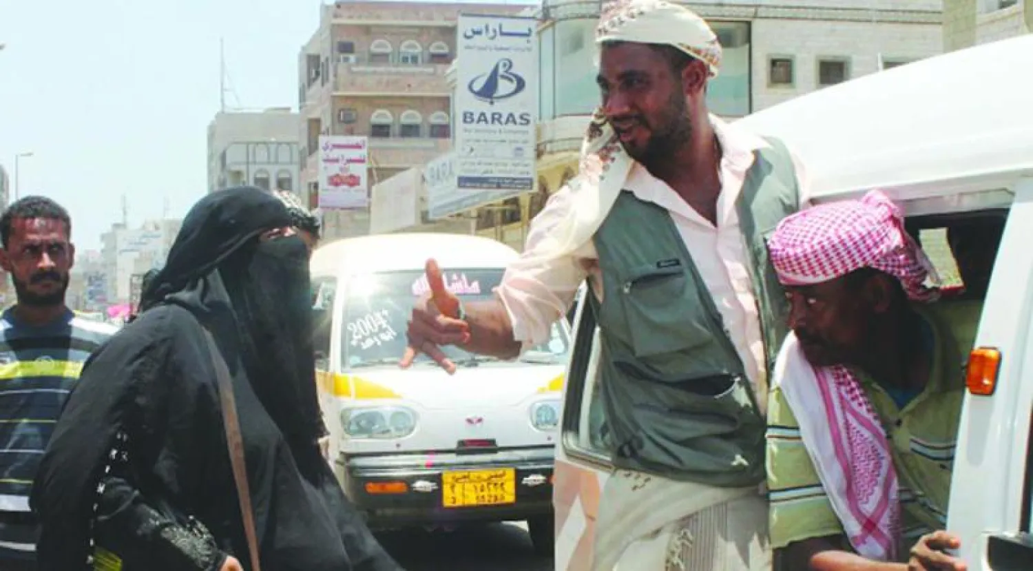 أم رائد مقاتلة جنوبية موالية للحكومة الشرعية ضد الحوثيين، تقول إنها حامل في الشهر الثامن، وتحمل بندقية آلية، أمام  نقطة تفتيش في منطقة الشيخ عثمان بميناء عدن في لقطة سابقة قبل تحرير المحافظات الجنوبية من ميليشيات التمرد (غيتي)