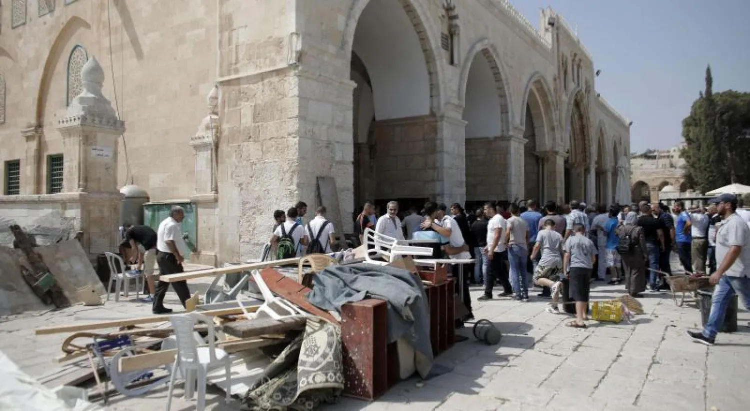 فلسطينيون تجمعوا عند مدخل الأقصى يعاينون ما تسببت به قوات الأمن الإسرائيلية من أضرار (أ.ف.ب)