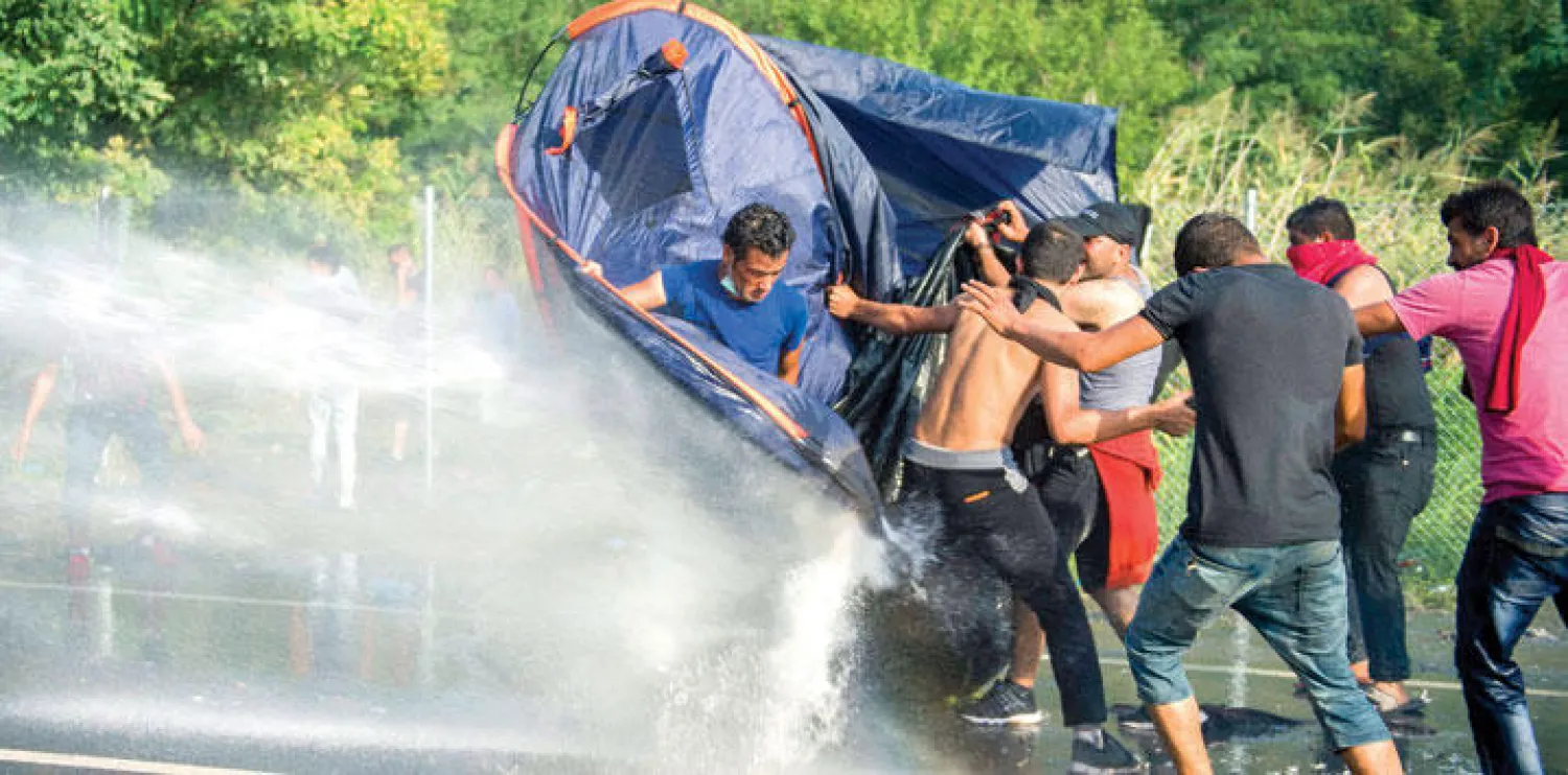 رجال شرطة من المجر يستخدمون خراطيم المياه القوية لتفريق مظاهرة لمهاجرين على الحدود قرب بلدة هورغوس (إ.ب.أ)