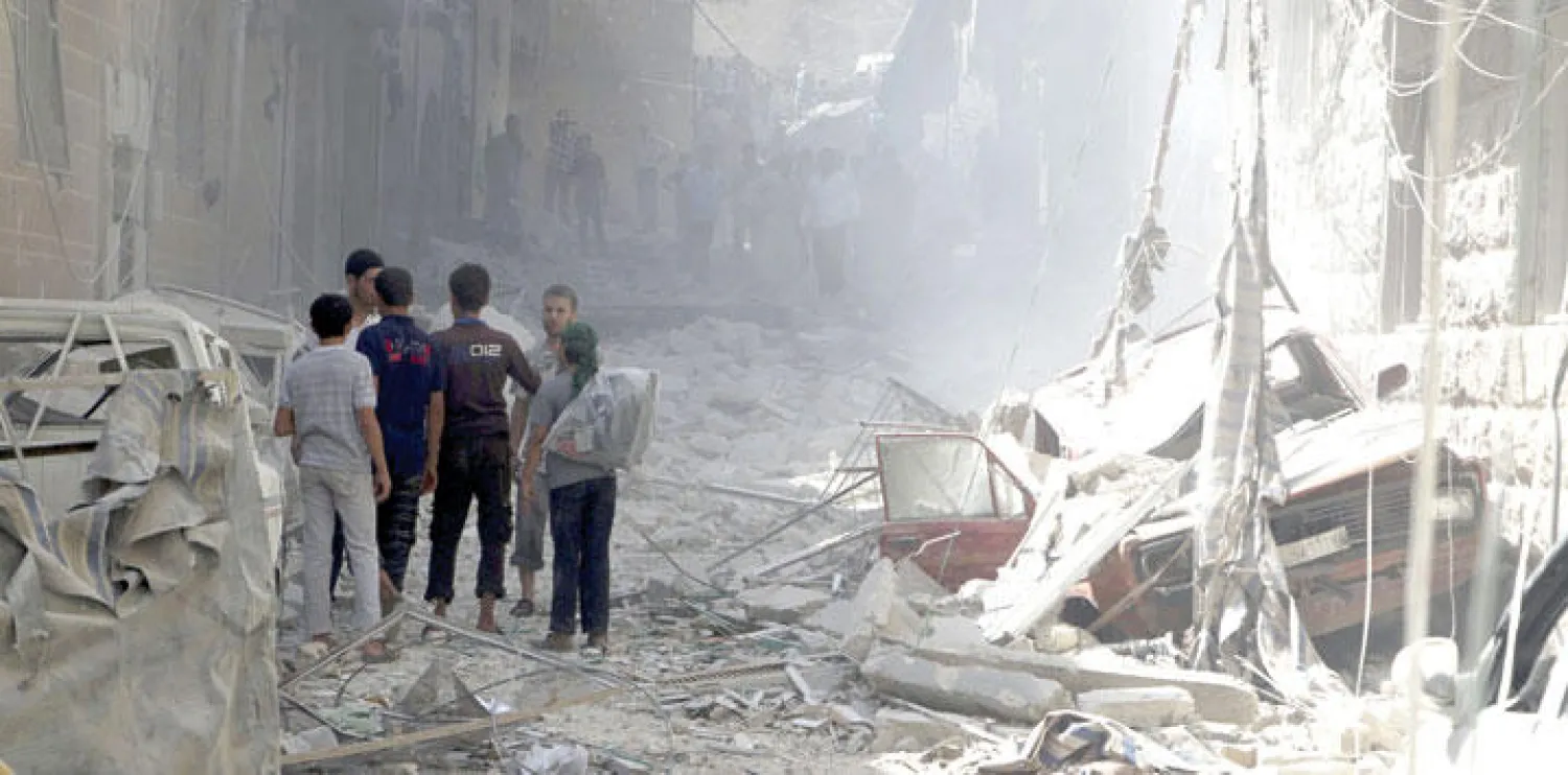 سوريون في شارع دمرته غارات جوية لطيران النظام في حي الأنصاري بحلب أمس (رويترز)