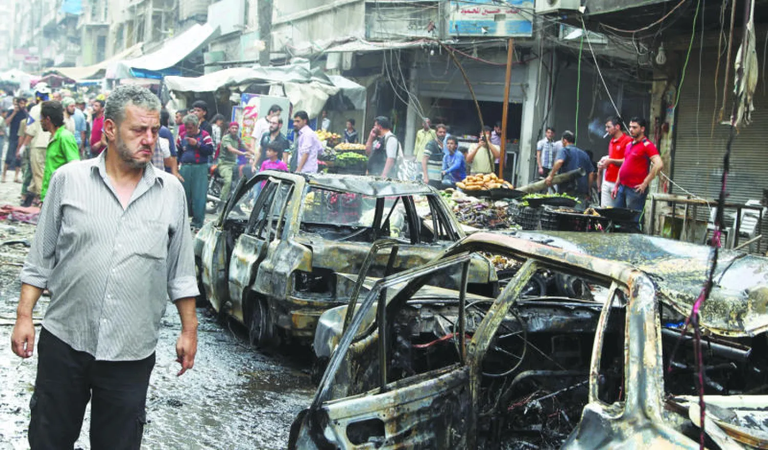 سكان من حي الشعار في مدينة حلب شمال سوريا يتفحصون الدمار الذي حل بالسوق المحلية بعد استهدافها بالطيران الحربي أمس، ومقتل 18 مدنيا على الأقل (رويترز)