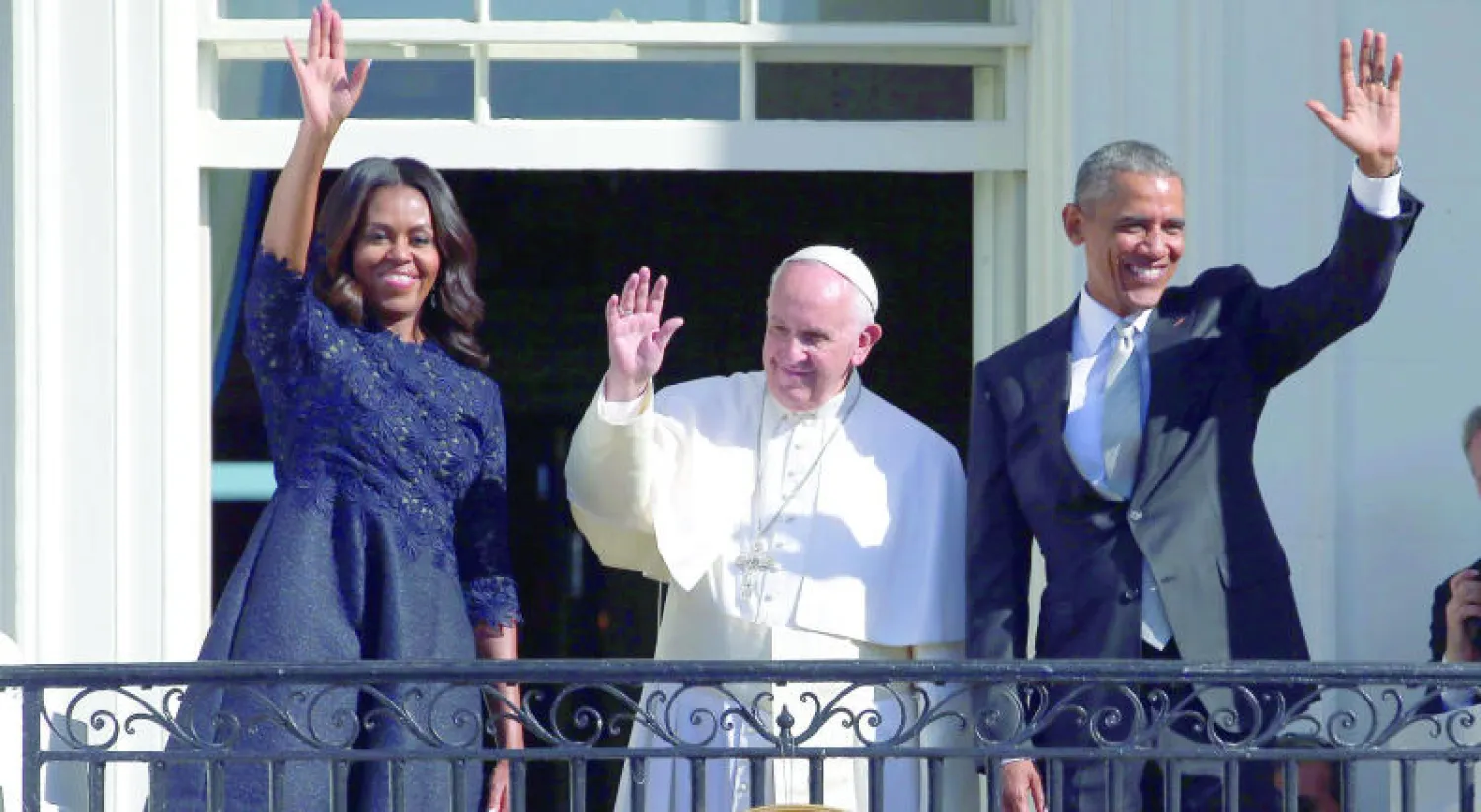 البابا فرنسيس متوسطا الرئيس الأميركي باراك أوباما وزوجته ميشيل يلوحون لأميركيين توافدوا بأعداد كبيرة لإلقاء التحية (إ.ب.أ)