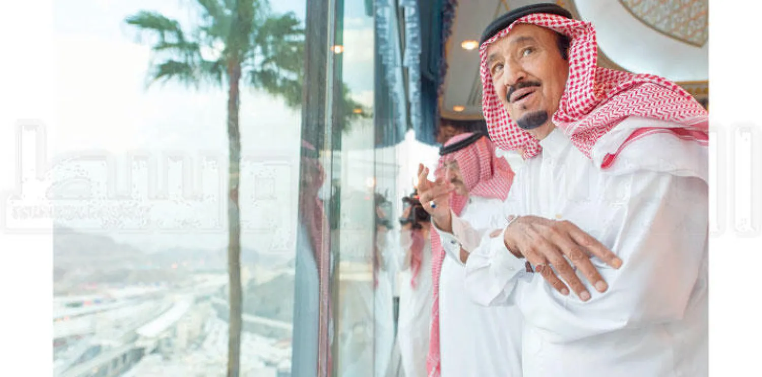 خادم الحرمين الشريفين الملك سلمان بن عبد العزيز يطل من شرفة زجاجية بالقصر الملكي في مشعر منى بعد وصوله قبل مغرب أمس ليباشر الإشراف على راحة وأمن وتنقلات الحجاج، ويبدو الأمير محمد بن نايف ولي العهد (تصوير: بندر الجلعود)