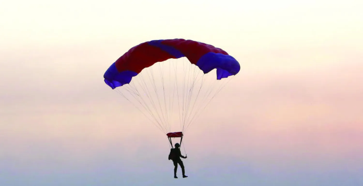 عنصر في ميليشيا الحشد الشعبي بعد قفزه بالمظلة من مروحية عراقية خلال تمرين في البصرة أول من أمس (أ.ب)