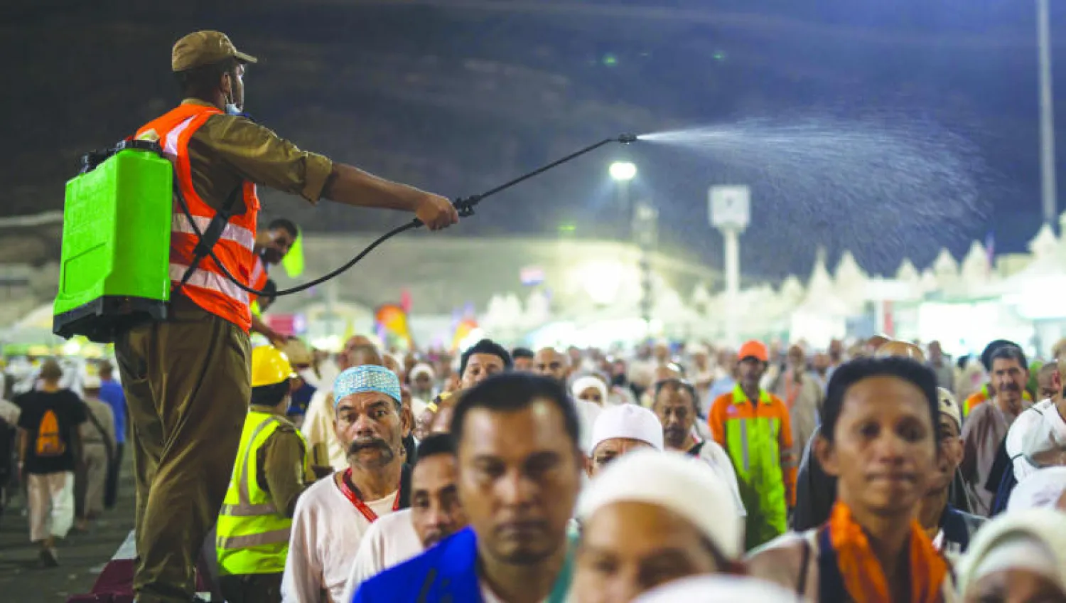 رجل أمن سعودي يرش المياه لتلطيف الجو الحار المحيط بالحجاج (أ.ب)