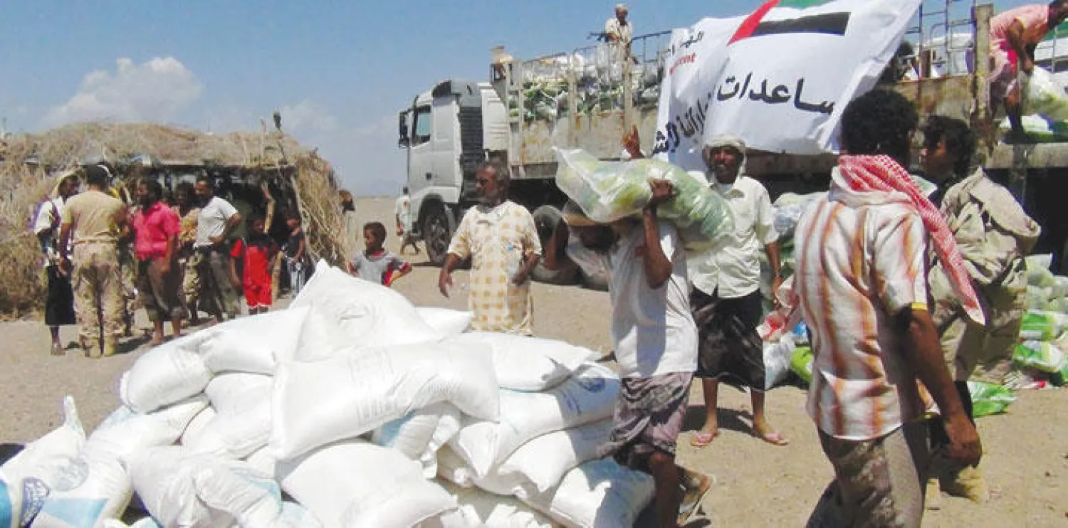 عمال يفرغون شاحنة تقل مساعدات غذائية إماراتية لليمنيين بالقرب من مضيق باب المندب المحرر من ميليشيا التمرد (رويترز)