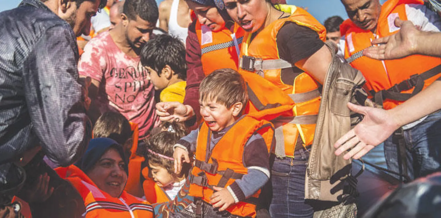 طفل سوري يبكي وسط مجموعة لاجئين وصلت إلى جزيرة ليسبوس اليونانية على متن مركب مطاطي أمس (إ.ب.أ)