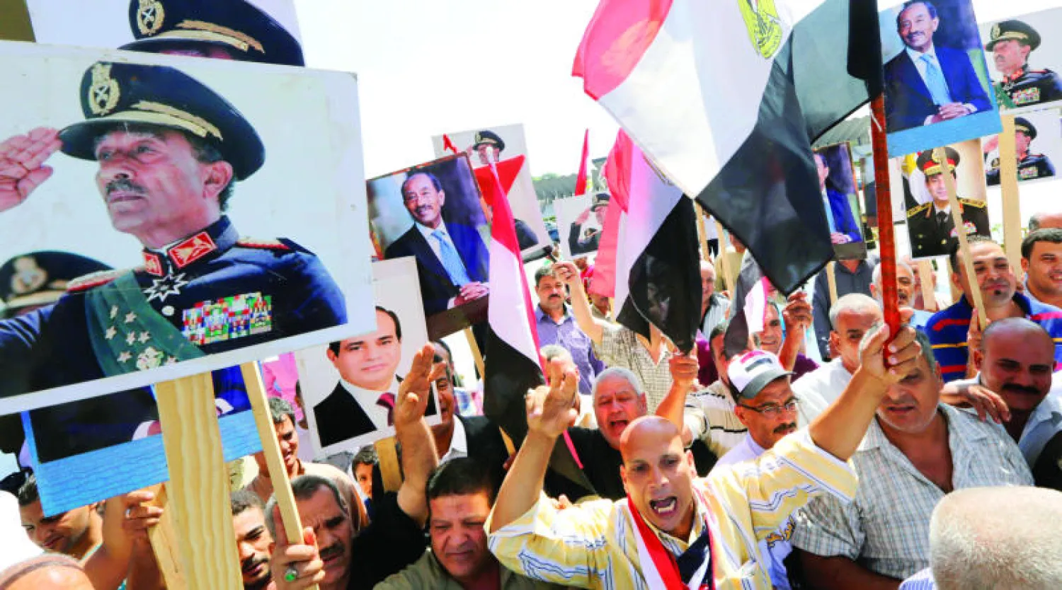 مصريون يشاركون في احتفالات أكتوبر ويرفعون صور الرئيسين الراحل أنور السادات والحالي عبد الفتاح السيسي بالقاهرة أمس (أ.ب)