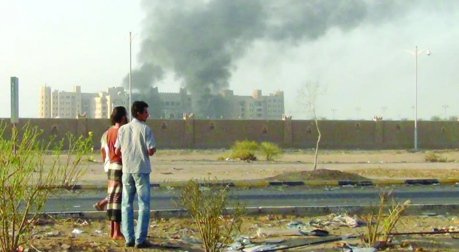 يمنيان يتابعان تصاعد الدخان من فندق القصر مقر الحكومة اليمنية في عدن الذي تعرض لتفجيرات إرهابية أمس (رويترز)