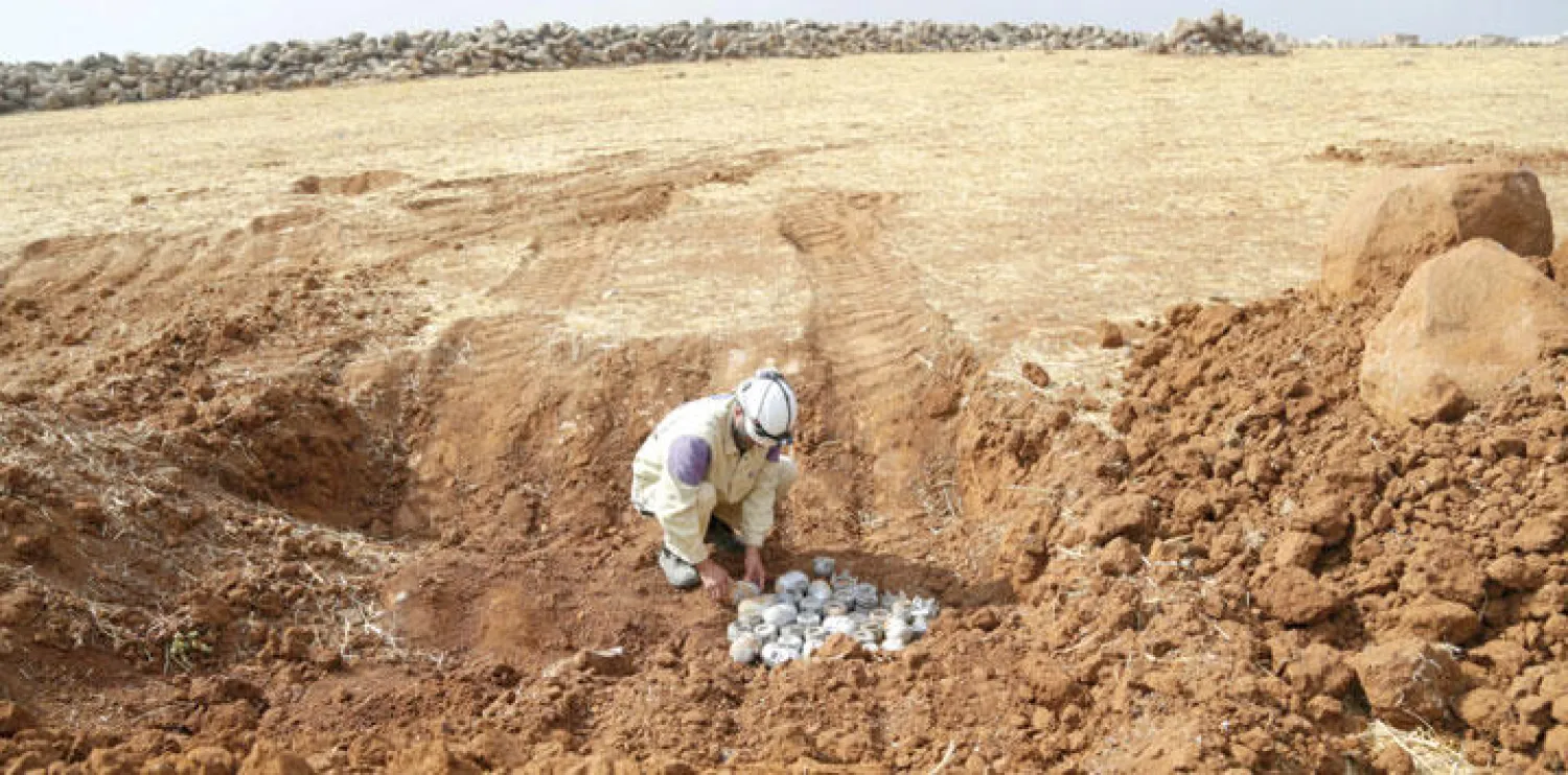 أحد العاملين في الدفاع المدني ينتزع قنبلة لم تنفجر سقطت من الطيران الروسي في قرية معصران بريف إدلب شمال سوريا (رويترز)
