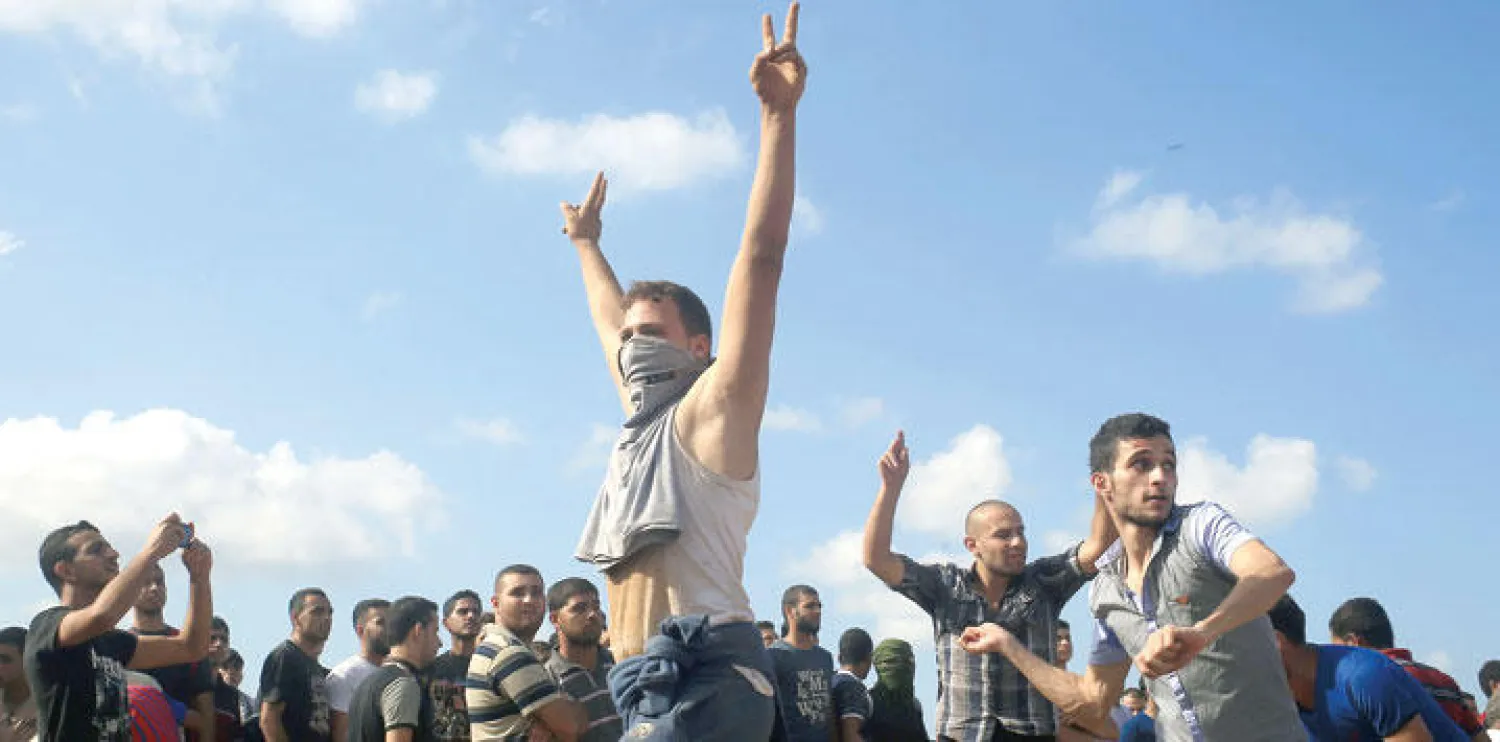 فلسطيني يرفع شارة النصر بيديه خلال المواجهات التي جمعت بين فلسطينيين وقوات إسرائيلية بالقرب من الحدود الفاصلة بين إسرائيل والضفة (أ.ف.ب)