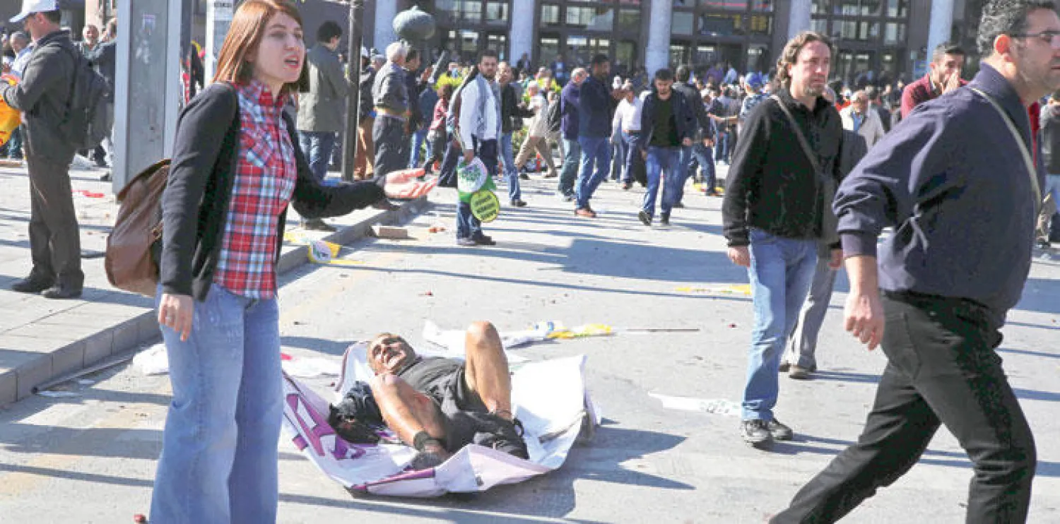 رجل أصيب في التفجيرين اللذين استهدفا تجمعًا من أجل السلام في أنقرة أمس ممدد على الأرض في انتظار وصول المسعفين إليه (أ.ب)