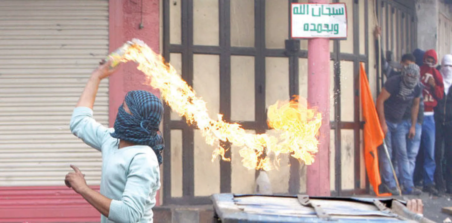ملثم فلسطيني يرمي جنود الاحتلال بزجاجة حارقة خلال مواجهات في مدينة الخليل بالضفة الغربية أمس (رويترز)