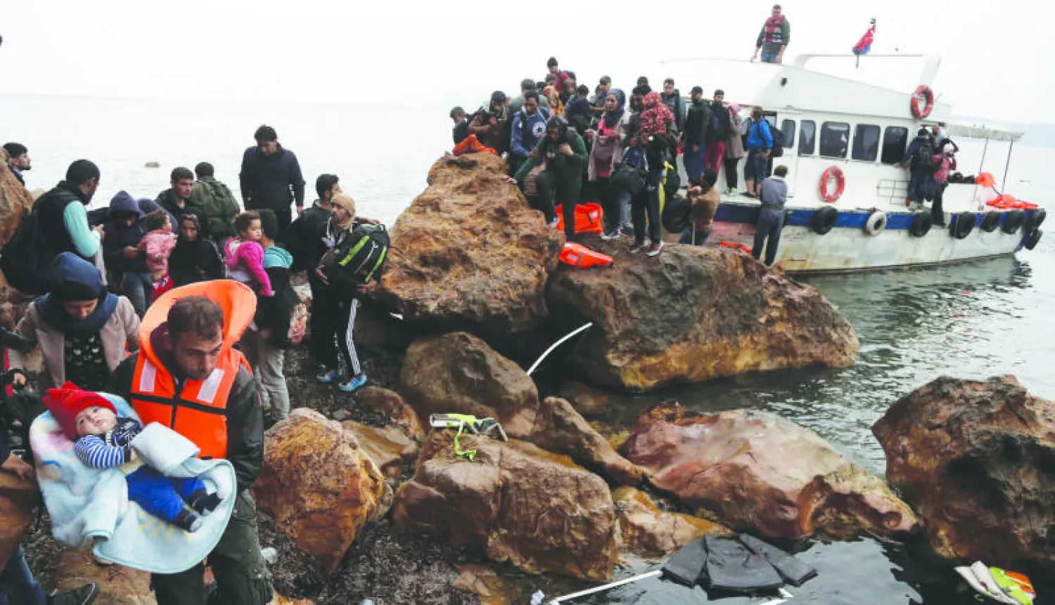 مهاجرون عند وصولهم إلى جزيرة ليسبوس اليونانية على متن قارب صيد مكتظ أمس (إ.ب.أ)
