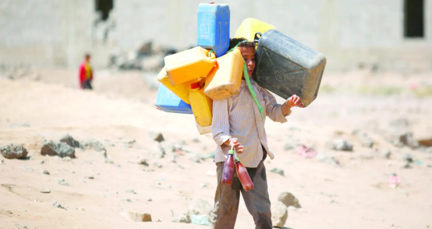 طفل يحمل عبوات بلاستيكية بهدف ملئها بالماء في إحدى ضواحي صنعاء أمس (أ.ب)
