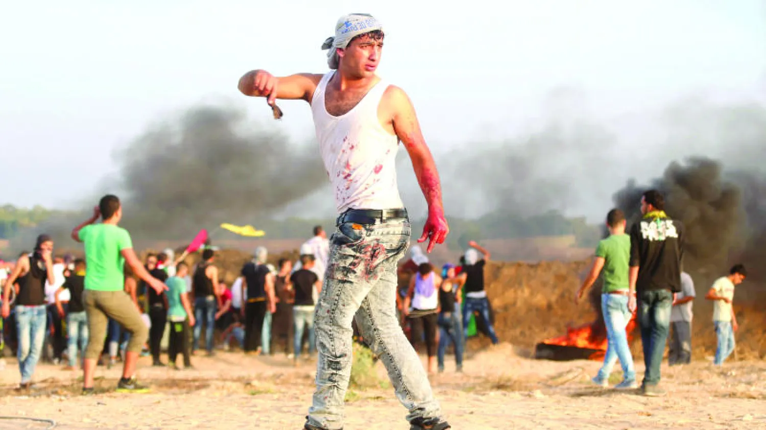 فلسطيني تلطخت ملابسه بالدماء خلال اشتباكات مع القوات الإسرائيلية بالقرب من الحدود بين اسرائيل ووسط قطاع غزة أمس (رويترز)