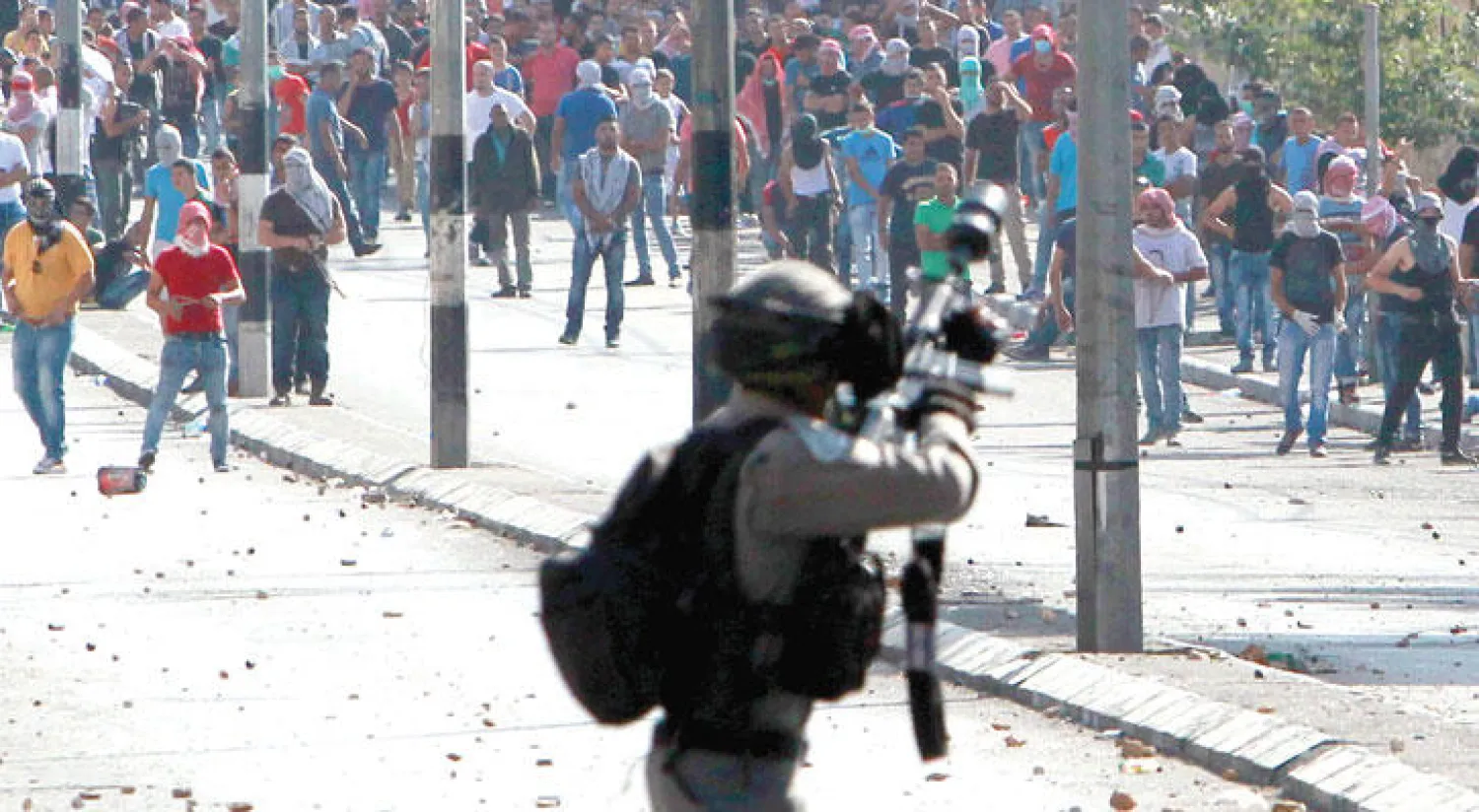 جندي إسرائيلي يوجه بندقيته نحو حشد فلسطيني خلال صدامات شهدتها مدينة بيت لحم أمس (أ.ف.ب)