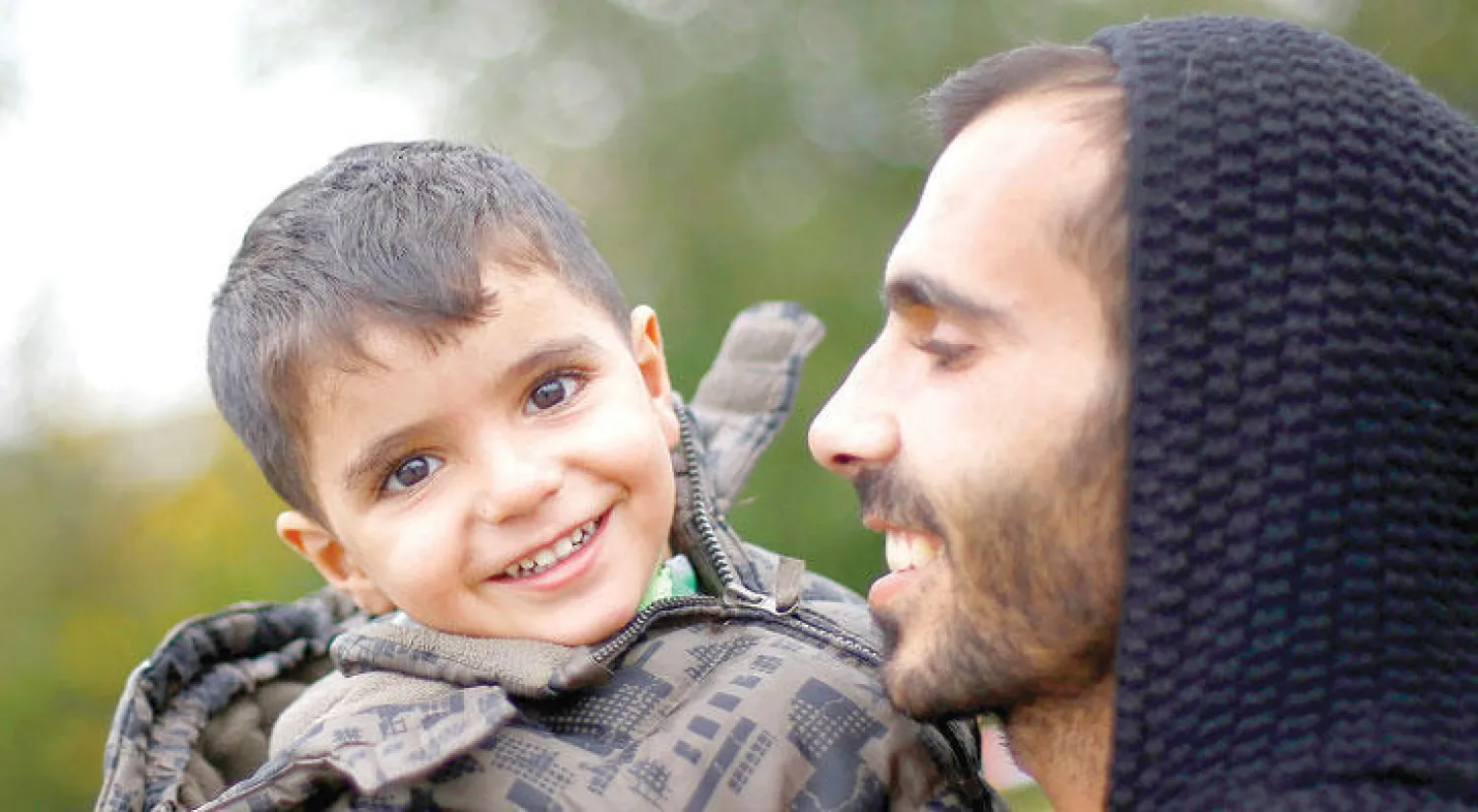 مهاجر يحمل طفلا بعد وصولهما إلى الحدود النمساوية - الألمانية أول من أمس (أ.ب)