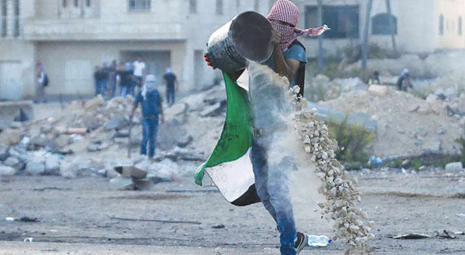فلسطيني يفرغ سطلاً من الحجارة بهدف استخدامها في مواجهة القوات الإسرائيلية في رام الله أمس (رويترز)