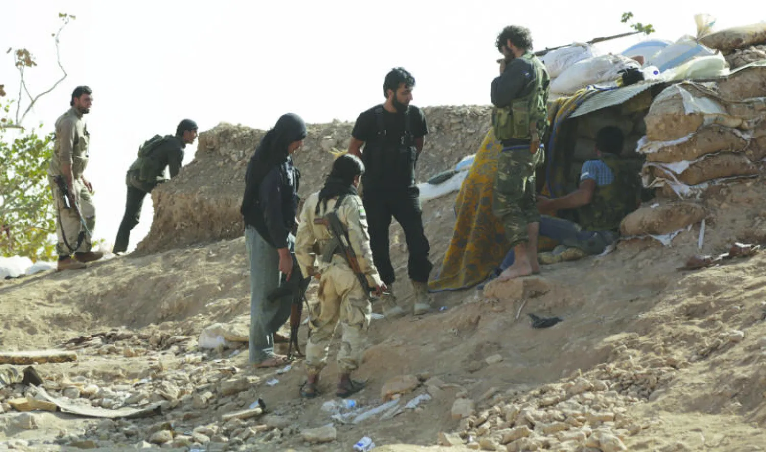 مقاتلون من الفرقة 101 في «الجيش السوري الحر» يتحصنون خلف أكياس رملية بالقرب من بلدة مورك بريف مدينة حماه، التي تتعرض منذ أسبوعين لهجوم بري من قوات الأسد مدعومة بغارات من الطيران الروسي (رويترز)