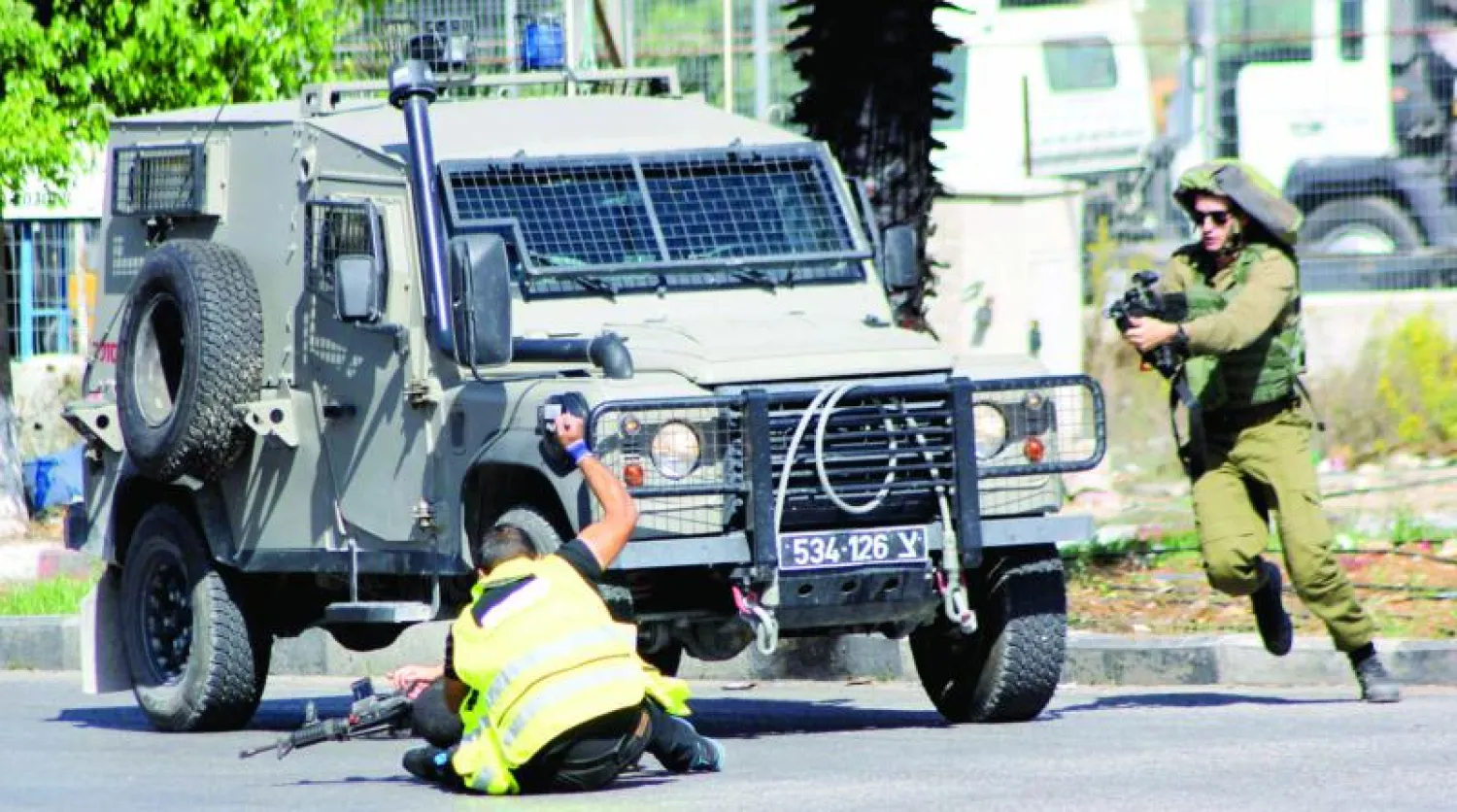 فلسطيني بزي صحافي قبل مقتله برصاص جندي إسرائيلي، يحاول طعن جندي آخر أمس (رويترز)
