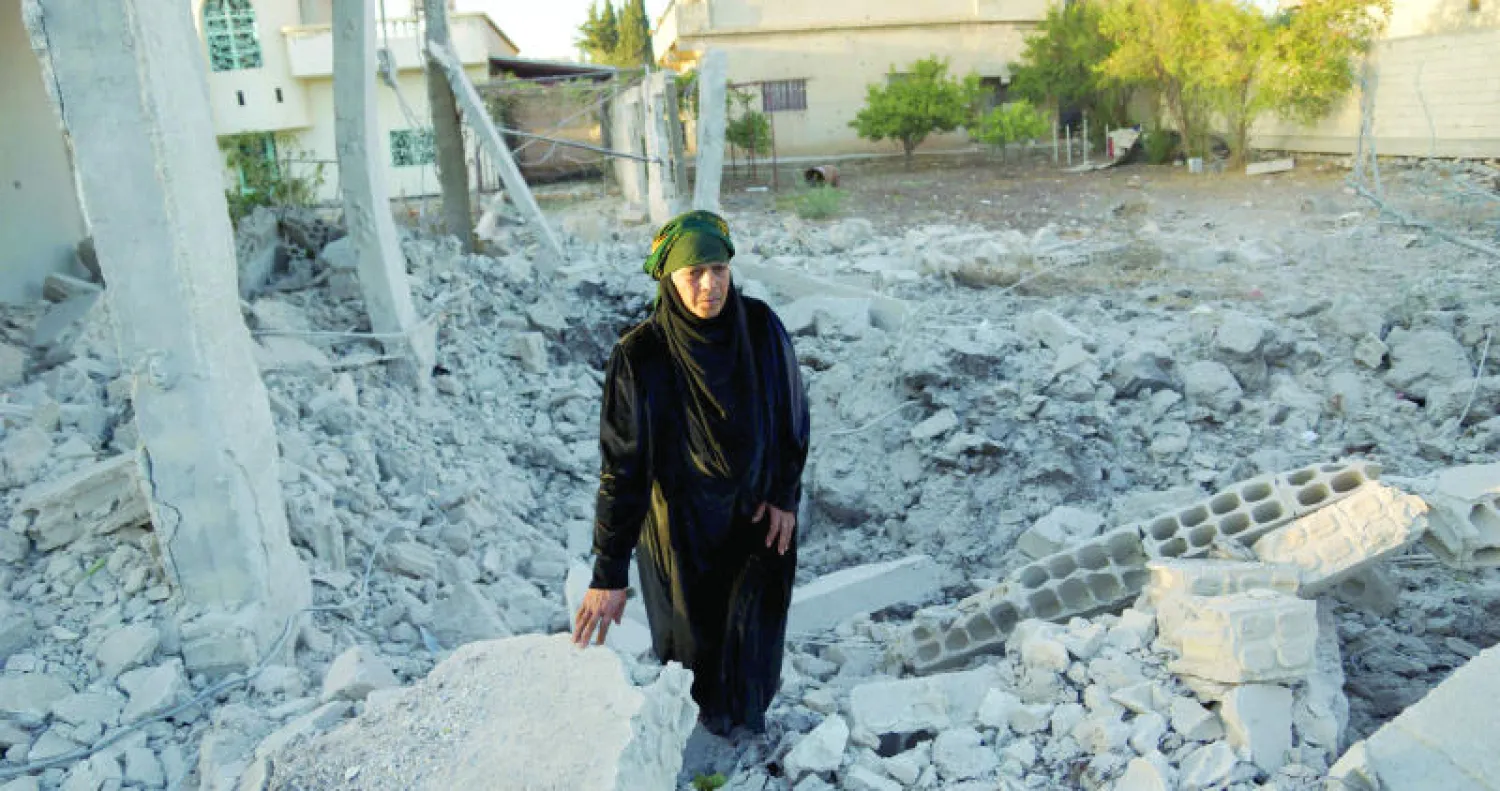 سورية تمشي بين ركام منزل تعرض للدمار بفعل أحد البراميل المتفجرة في منطقة نوى بدرعا (رويترز)