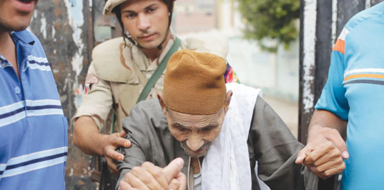 جندي من القوات المسلحة يساعد عجوزا مصريا على الدخول إلى لجنة انتخابية في الجيزة أمس (رويترز)