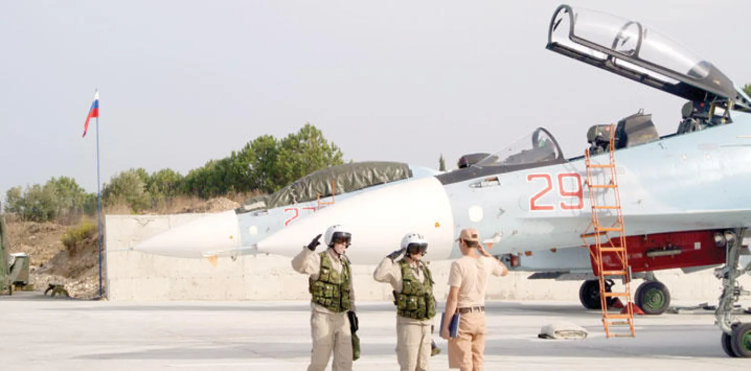الطاقم الأرضي الروسي في مطار القاعدة الجوية حميميم بسوريا يشير إلى الطيارين بأن الطائرة الخاصة جاهزة للإقلاع في مهمة قتالية أمس (أ.ب)