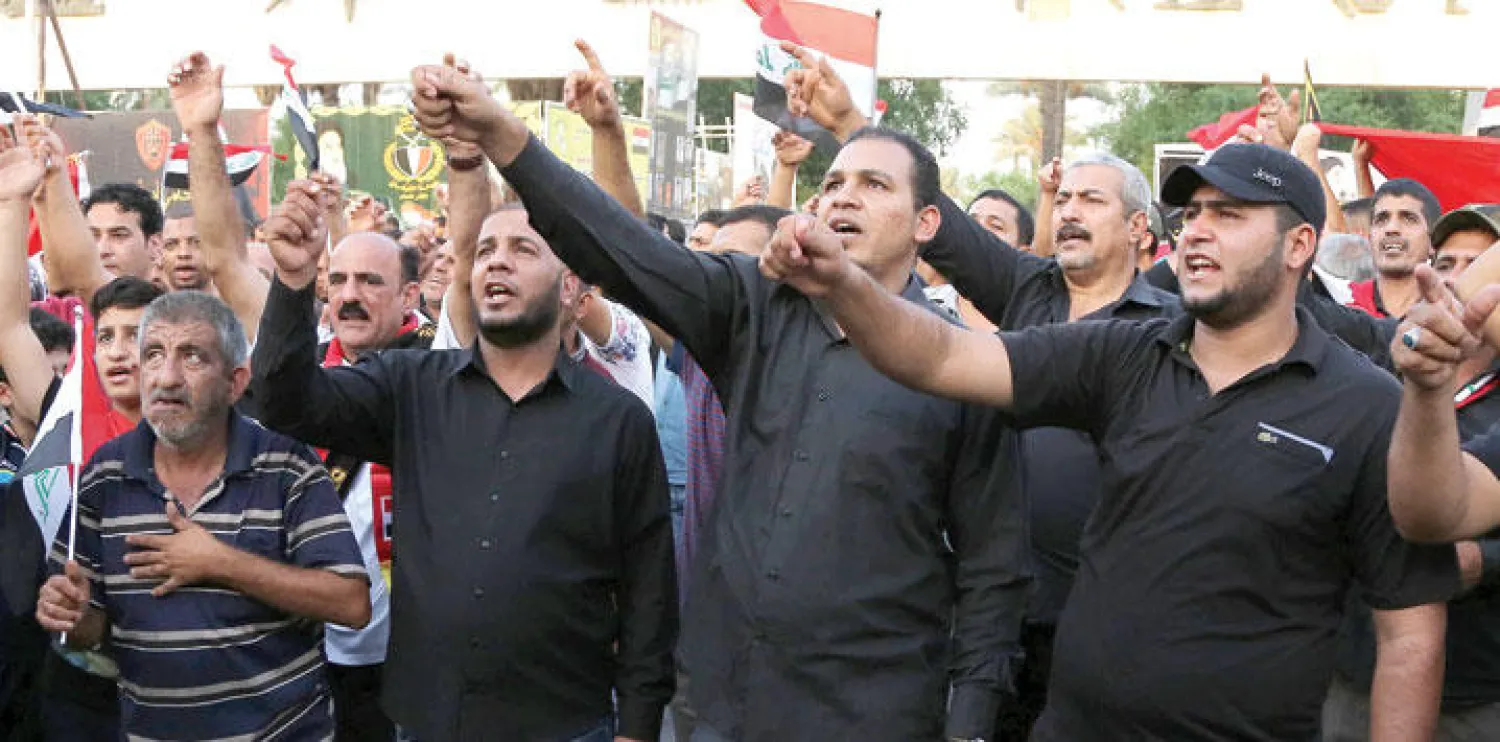 متظاهرون عراقيون ويرددون الهتافات ويلوحون بالأعلام في ساحة التحرير وسط بغداد أمس (أ.ب)