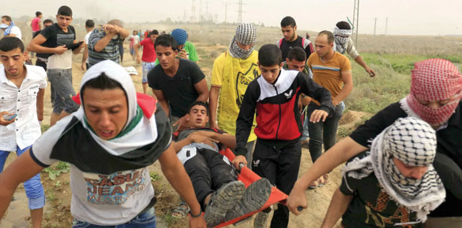 فلسطينيون يحملون زميلا لهم أصيب خلال المواجهات التي شهدها قطاع غزة أمس (أ.ف.ب)