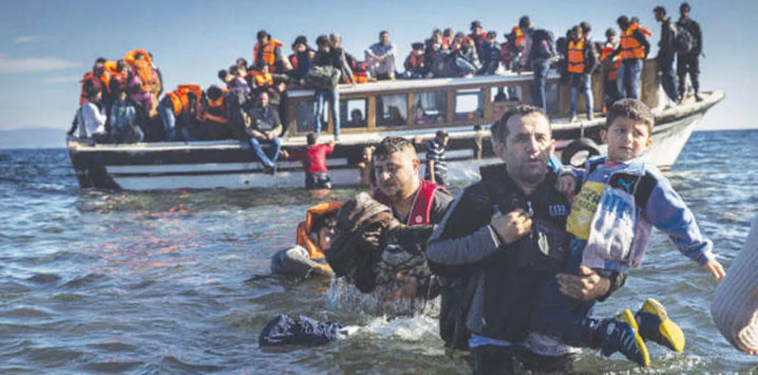 مهاجرون من سوريا والعراق لدى وصولهم على متن قارب إلى جزيرة ليسبوس اليونانية قادمين من السواحل التركية أمس (أ.ب)
