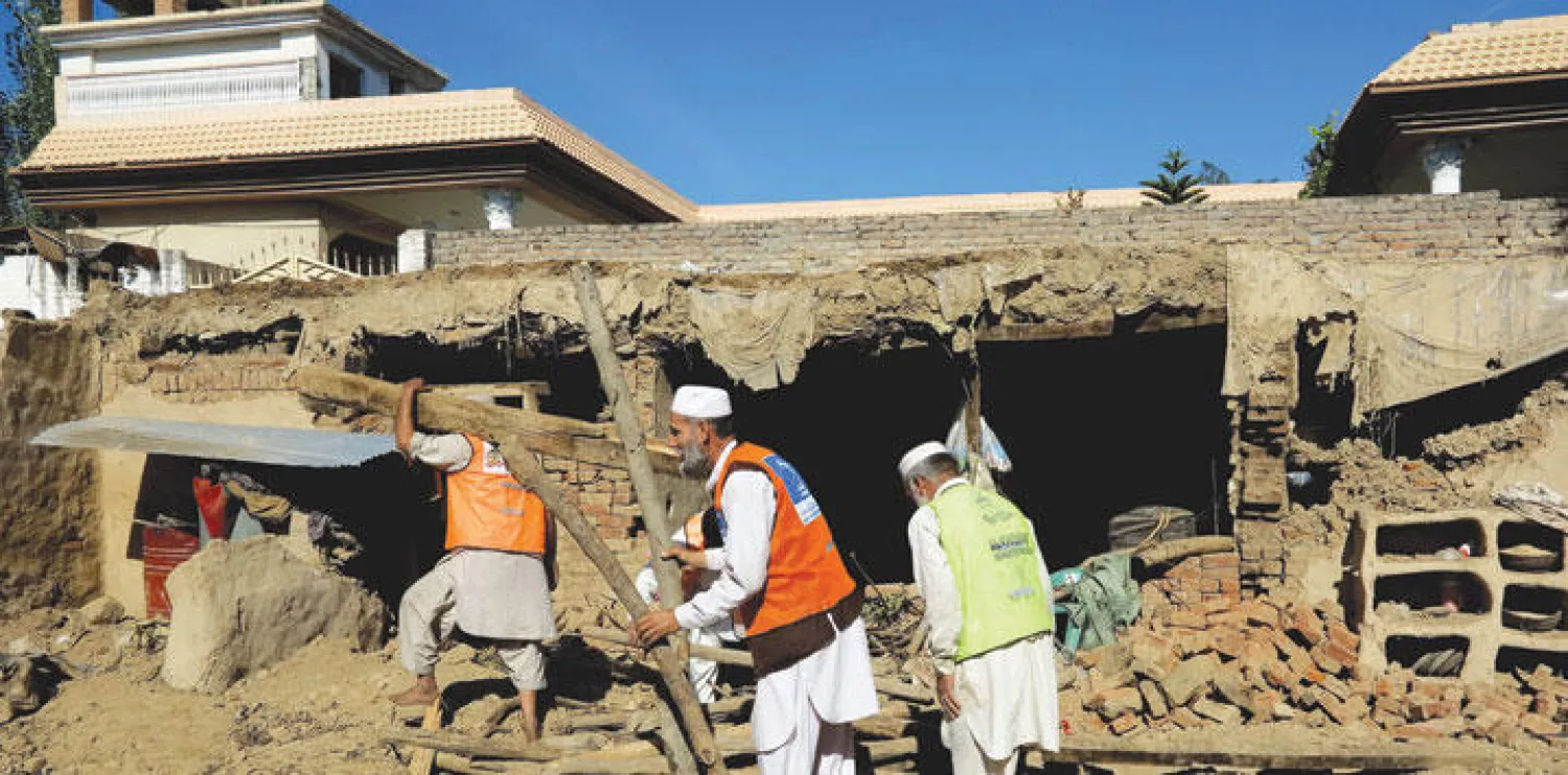 متطوعون باكستانيون يساعدون سكان القرى المتضررة من الزلزال القوي الذي ضرب أفغانستان وباكستان منذ أربعة أيام (أ.ف.ب)