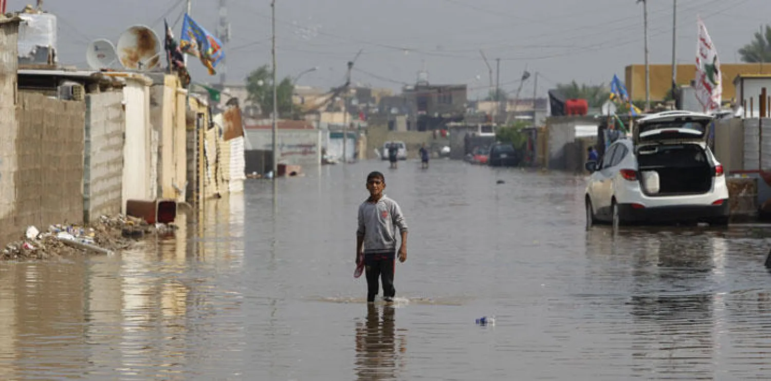 صبي يقف وسط شارع تغمره مياه الأمطار في بغداد أمس (رويترز)