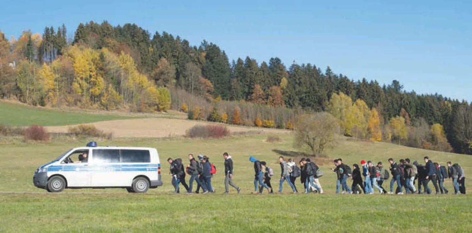 مهاجرون يتبعون سيارة للشرطة الألمانية بعد عبورهم من النمسا أمس (إ.ب.أ)