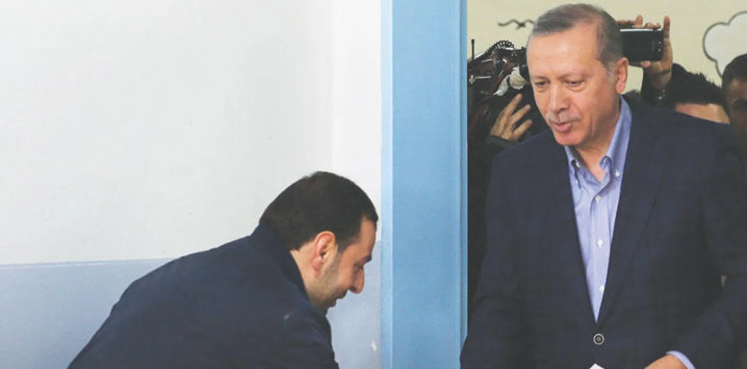 الرئيس التركي رجب طيب إردوغان يصافح موظفا انتخابيا وهو يصل إلى مركز اقتراع في إسطنبول للإدلاء بصوته أمس (أ.ب)