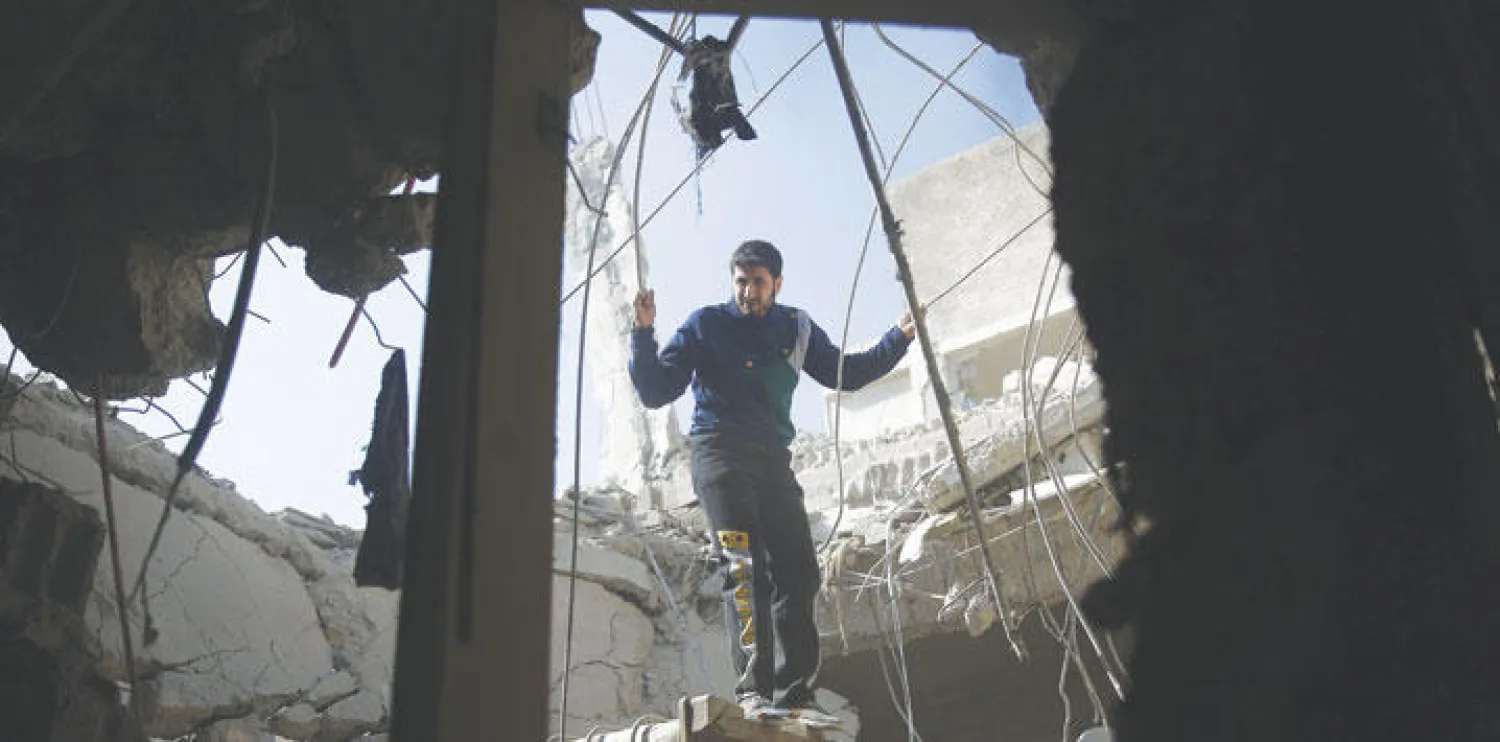 رجل من سكان دوما بريف دمشق يتفحص الدمار الذي لحق بالمنطقة جراء قصف الطيران الحربي للمدينة أمس (أ.ف.ب)